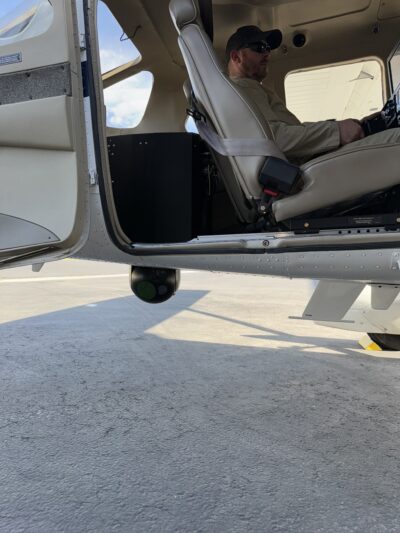 An image of a Cessna 206 outfitted with RIS's seat rail extensions and payload retraction system, part of the C206H Airborne Law Enforcement Solution