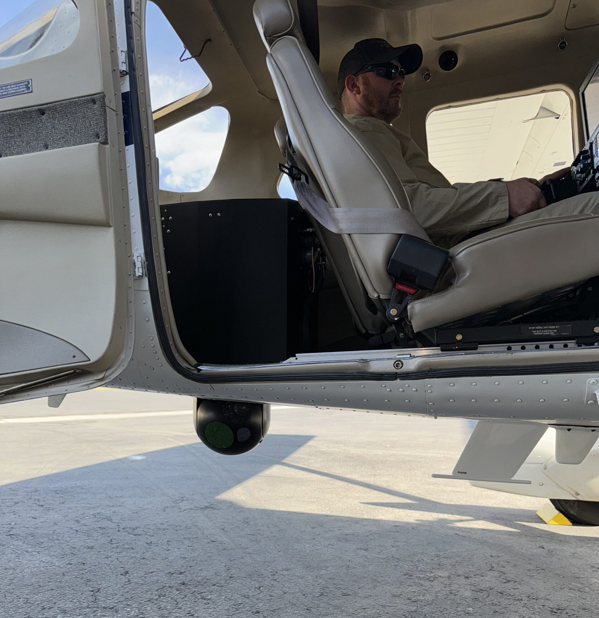 An image of a Cessna 206 outfitted with RIS's seat rail extensions and payload retraction system, part of the C206H Airborne Law Enforcement Solution